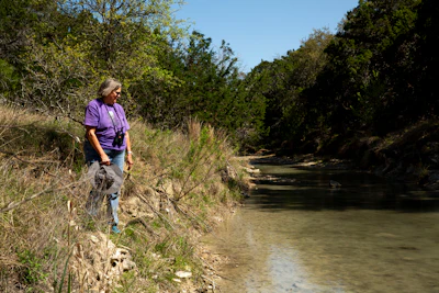 Margo Denke, co-founder of the group Friends of Hondo Canyon, surveys a stretch of Commissioners Creek on her ranch in Bandera County, Texas. Credit: Dylan Baddour/Inside Climate News