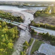 Aerial view of flooded river valley with damaged infrastructure and submerged roads during natural disaster