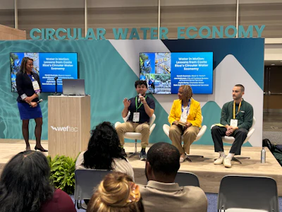 Panel discussion on circular water economy at conference with four speakers and audience members seated in front of branded backdrop.