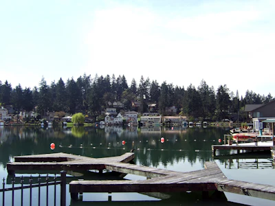Waterfront homes and docks reflected in calm lake water surrounded by evergreen forest