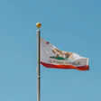 California state flag waving on a flagpole against a clear blue sky